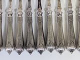 six forks and six knives on a white surface