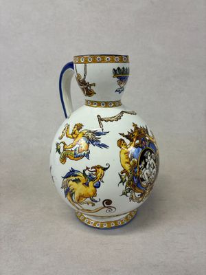a white vase with a blue handle sitting on a table