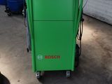 une photo d'une machine verte dans un garage, à côté d'une poubelle bleue