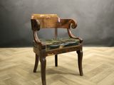 une chaise en bois avec une assise en cuir, posée sur un parquet