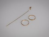 a close up of two gold rings and a stick on a white surface