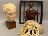 trois œuvres d'art sont exposées dans une vitrine posée sur une surface blanche