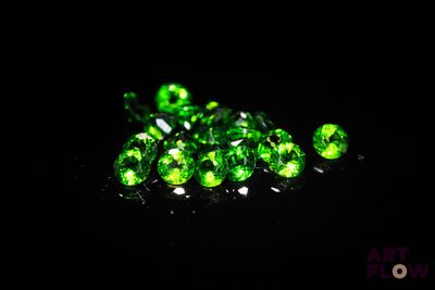 a pile of green crystals sitting on top of a black surface
