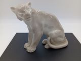 statue d'un chat assis sur un socle noir, sur fond blanc