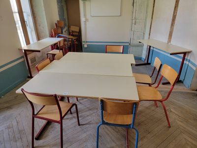 tables and chairs in an empty classroom with a white board on the wall