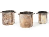 three metal pots sitting next to each other on top of a white surface