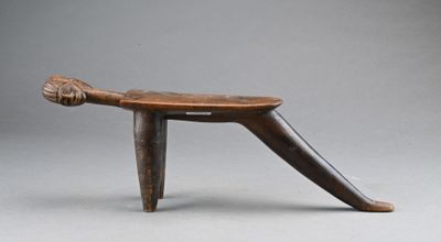 un vieux tabouret en bois muni d'une poignée en bois, sur fond gris