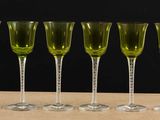 six green wine glasses lined up on a table