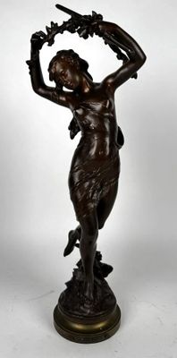 une statue antique en bronze représentant une femme tenant un oiseau