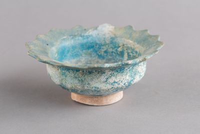 un petit bol bleu posé sur une table, avec un socle en bois