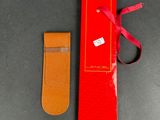 pair of red and tan leather bookmarks with a red ribbon tied to them