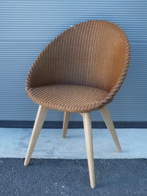 une chaise en osier avec des pieds en bois et une assise marron