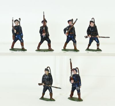 several figurines of men in uniforms with weapons on a white surface