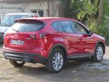 a red mazda cx - 5 parked in front of a house