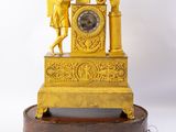 a gold clock on a wooden stand on a white background