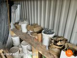many buckets and cans of paint in a storage area