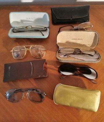several pairs of glasses and glasses case sitting on a wooden table