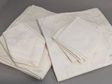 plusieurs serviettes blanches pliées, ornées de motifs brodés, posées sur une table