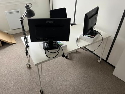 two computer monitors on a white desk in a room