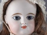 a close up of a doll wearing a white dress and a bonnet