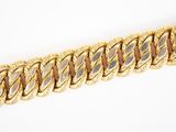 gros plan d'un bracelet en chaîne en or sur une surface blanche