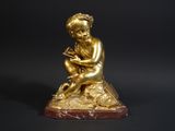 a gold figurine of a boy sitting on a rock