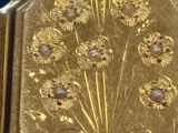 a close up of a gold plated watch with flowers on it