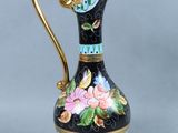 a black and gold vase with flowers painted on it