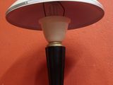 une photo représentant une lampe de table posée sur une surface rouge, avec un mur rouge en arrière-plan