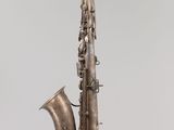 an old saxophone hanging from a string on a gray background