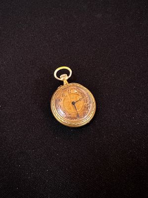 an old pocket watch with a gold chain on a black cloth