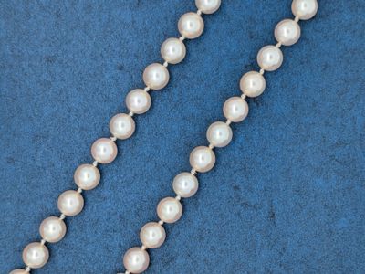 un gros plan d'un collier de perles blanches sur fond bleu