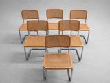 six chairs with a wicker seat are arranged in a row