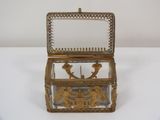 antique brass and glass box with figures on it on a white surface