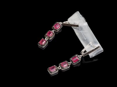 un gros plan sur une paire de boucles d'oreilles en saphir rose sur fond noir