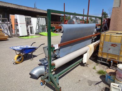 a large roll of fabric on the ground next to a cart