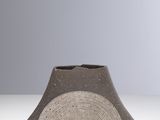 un vase gris et blanc posé sur une table blanche, sur fond gris