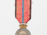 une vieille médaille ornée d'un ruban rouge, bleu et noir sur fond blanc