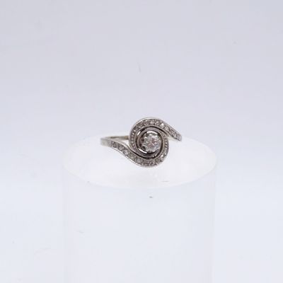 un gros plan d'une bague en diamant posée sur un socle blanc