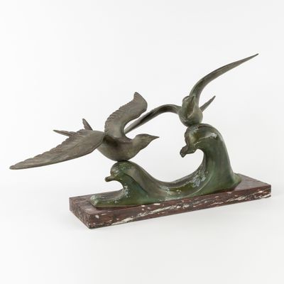 sculpture en bronze représentant deux oiseaux volant au-dessus d'une vague, posée sur un socle en marbre