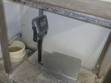 une photo d'une salle de bains avec un pèse-personne numérique posé par terre