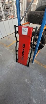 une borne d'incendie rouge posée dans un garage, à côté de quelques pneus