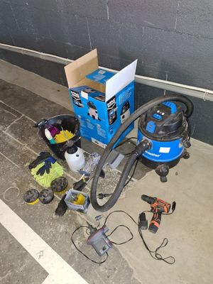 une boîte bleue contenant un aspirateur et d'autres outils, posée par terre