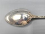 silver plated spoon with a design on it on a white surface