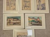 six dessins encadrés représentant des bâtiments et une voiture sont posés par terre
