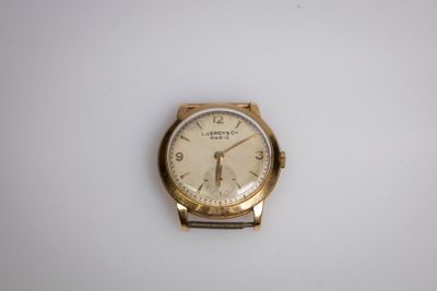 une image d'une montre-bracelet en or sur une surface blanche