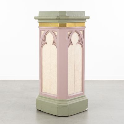 une image représentant un socle rose et vert surmonté d'une horloge