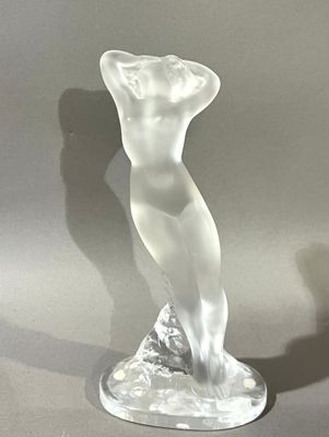 une sculpture en verre représentant une femme debout sur un socle