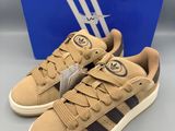 une paire de baskets Adidas de couleur beige et noire, accompagnée d'une boîte bleue