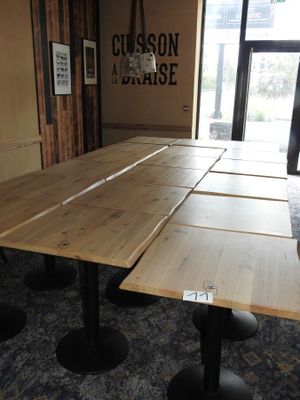des tables et des tabourets dans une pièce où est accrochée une affiche au mur
